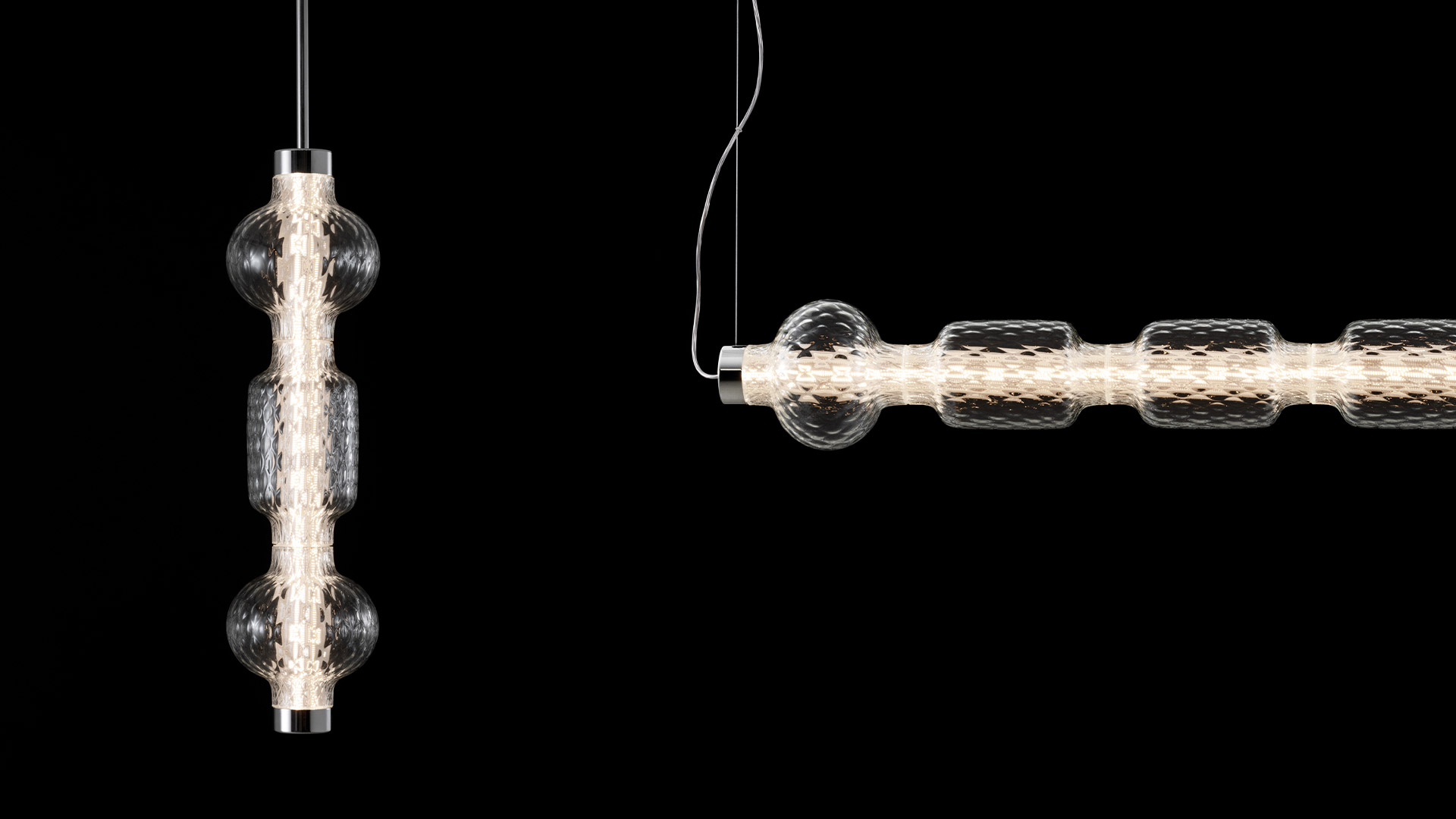 Two Artemide Alambicco pendant lamps with textured glass spheres and cylindrical LED core, suspended on thin black cords against dark background