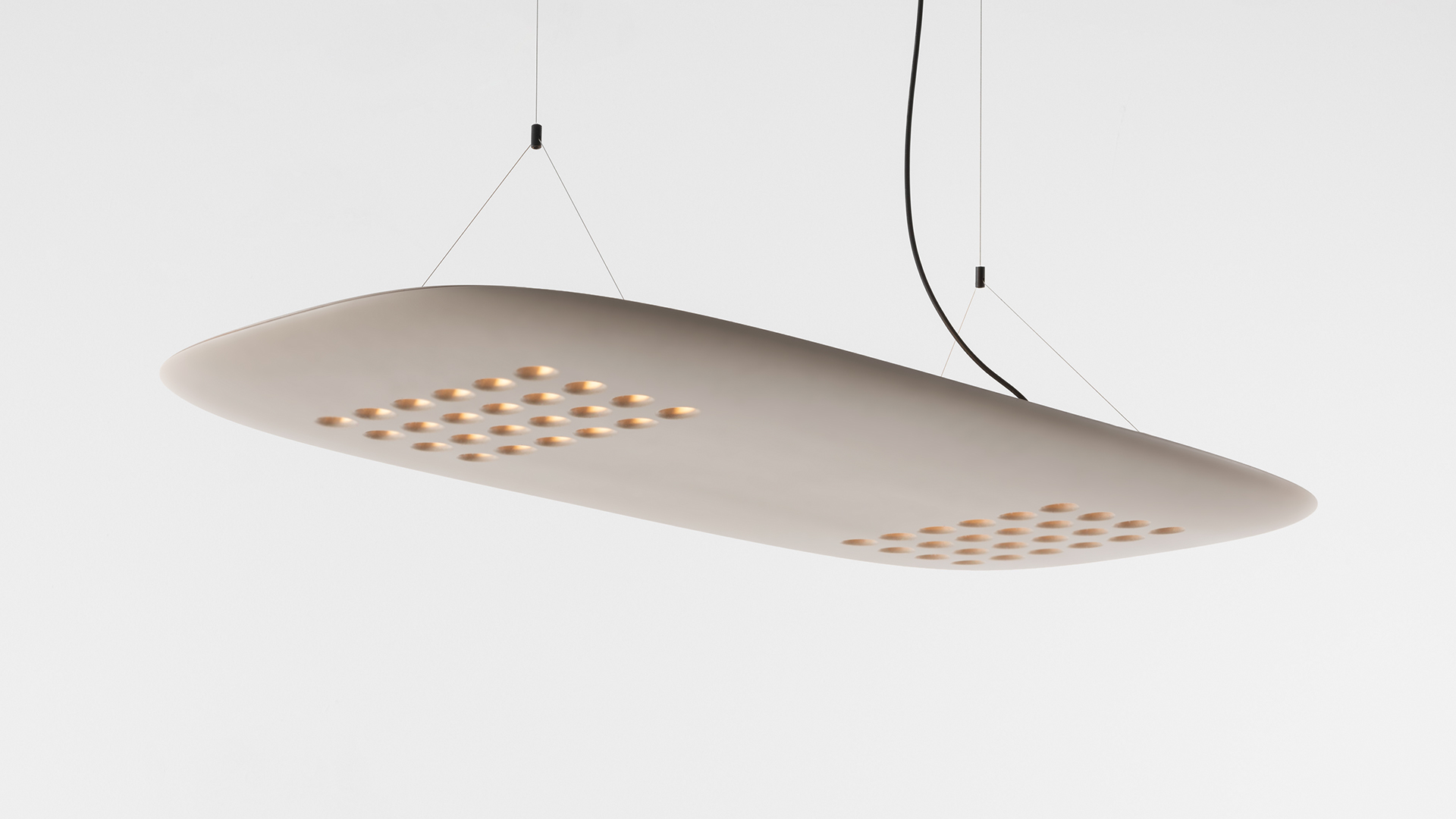 Lampada a sospensione ovale Artemide ALE.01 in finitura legno caldo che illumina uno spazio di lavoro scuro con due tavoli con struttura nera
