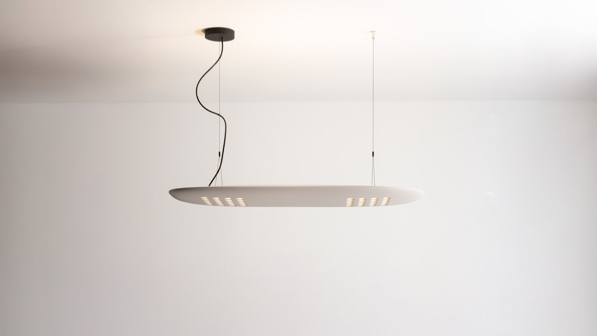 Lampada a sospensione Artemide ALE.01: grande diffusore ovale grigio con file di LED dorati sul lato inferiore, sospesa da cavo nero