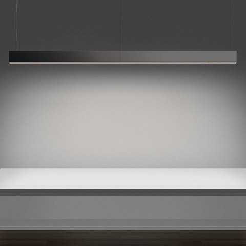 Artemide Algoritmo pendant lamp: sleek dark linear LED fixture suspended over a white surface, emitting soft downward light