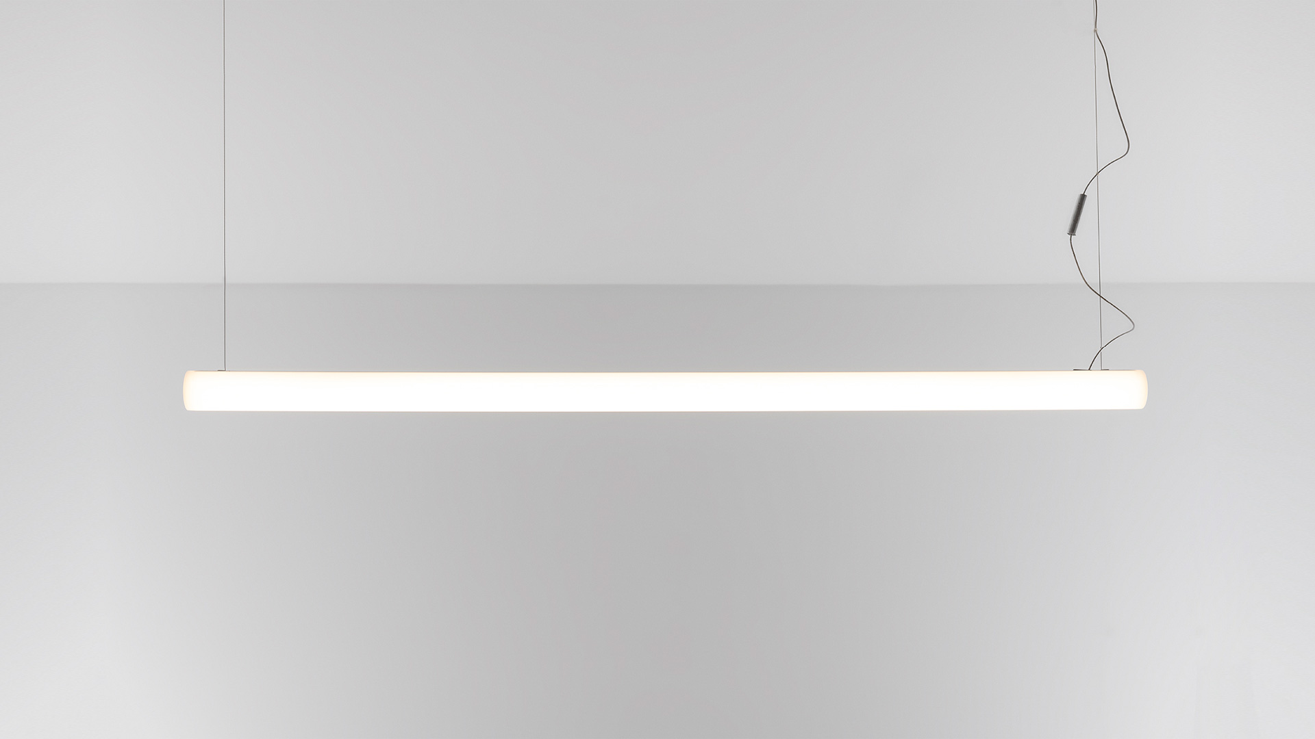 Lampade a sospensione Artemide Alphabet of Light Linear che formano un grande arco sopra un banco reception in marmo dell'Associazione Italiana Sommelier