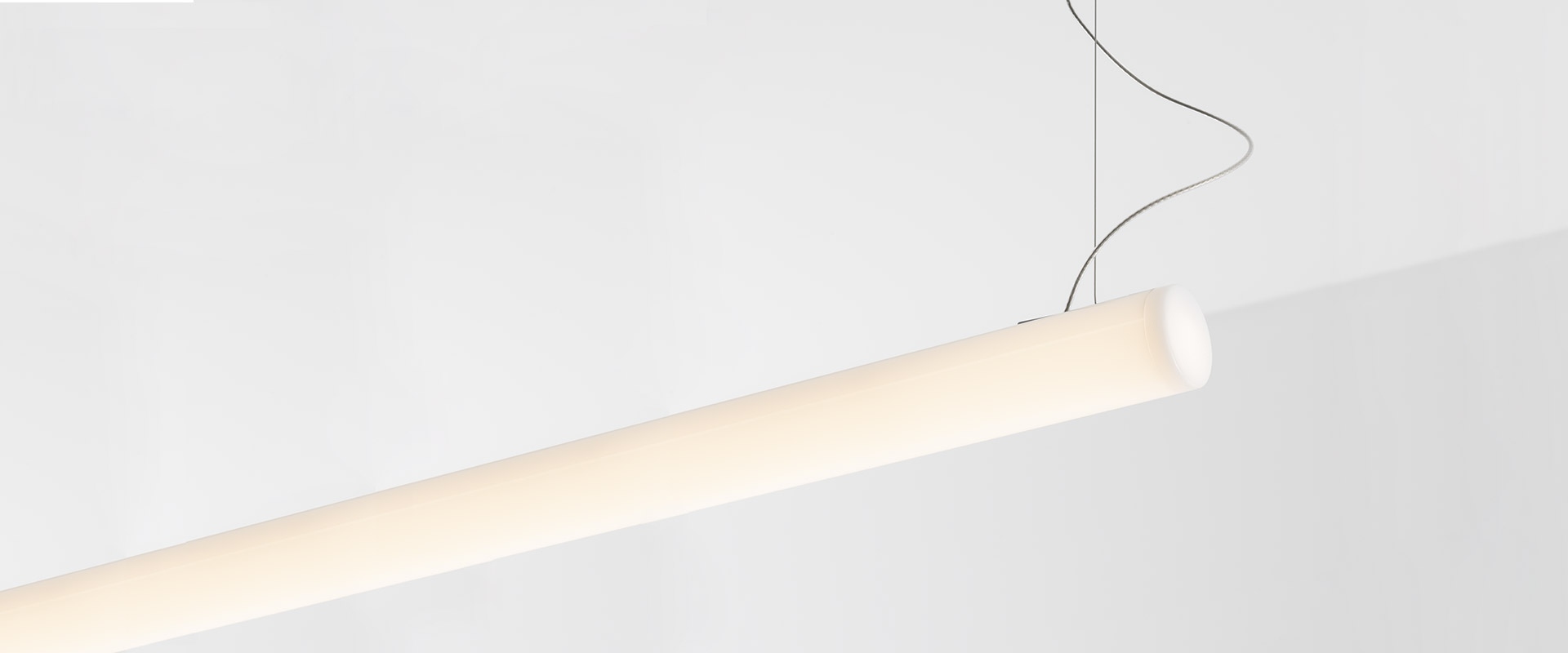 Sala riunioni moderna con lampada a sospensione Artemide Alphabet of Light Linear a forma di L sopra un tavolo conferenze in legno chiaro con sedie grigie