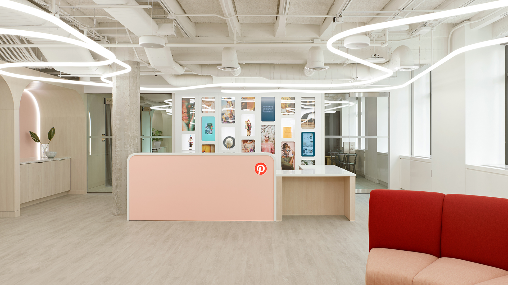 Lounge ufficio moderno con installazione a sospensione Artemide Alphabet of Light System, sedute colorate e vista panoramica sulla città al crepuscolo