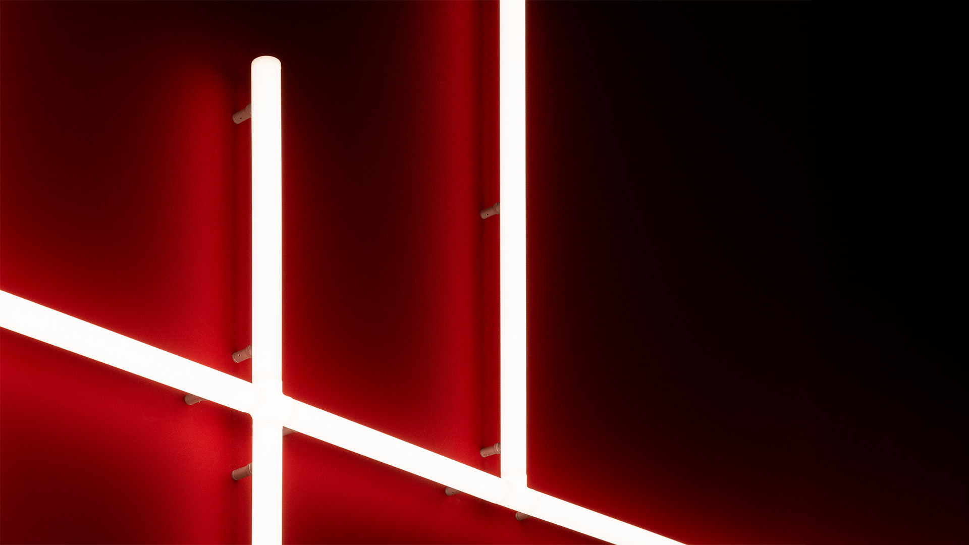 Reception ufficio Pinterest con sistemi circolari a sospensione Artemide Alphabet of Light su soffitto bianco a vista, scrivania rosa, divano rosso