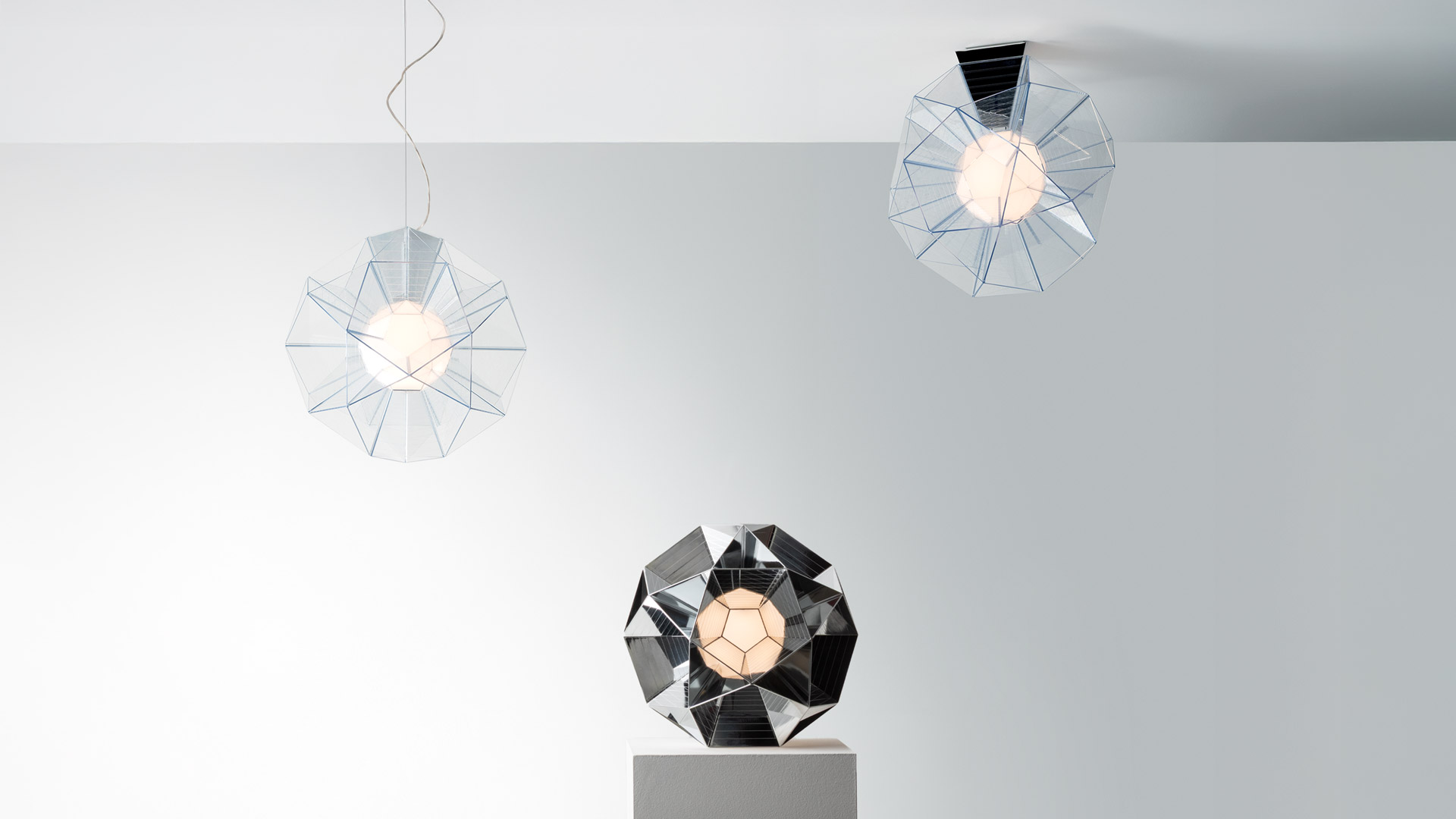 Artemide Arctic pendant lamp with faceted geometric chrome shade resembling a diamond, emitting warm light from its center