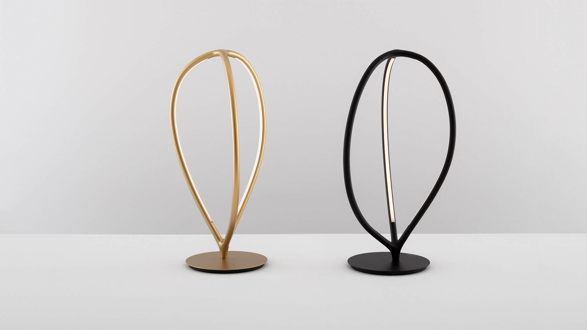 Lampade Artemide Arrival nere: due sospensioni, una lampada da tavolo su cubo, una da terra con cornici LED ovali ad anello