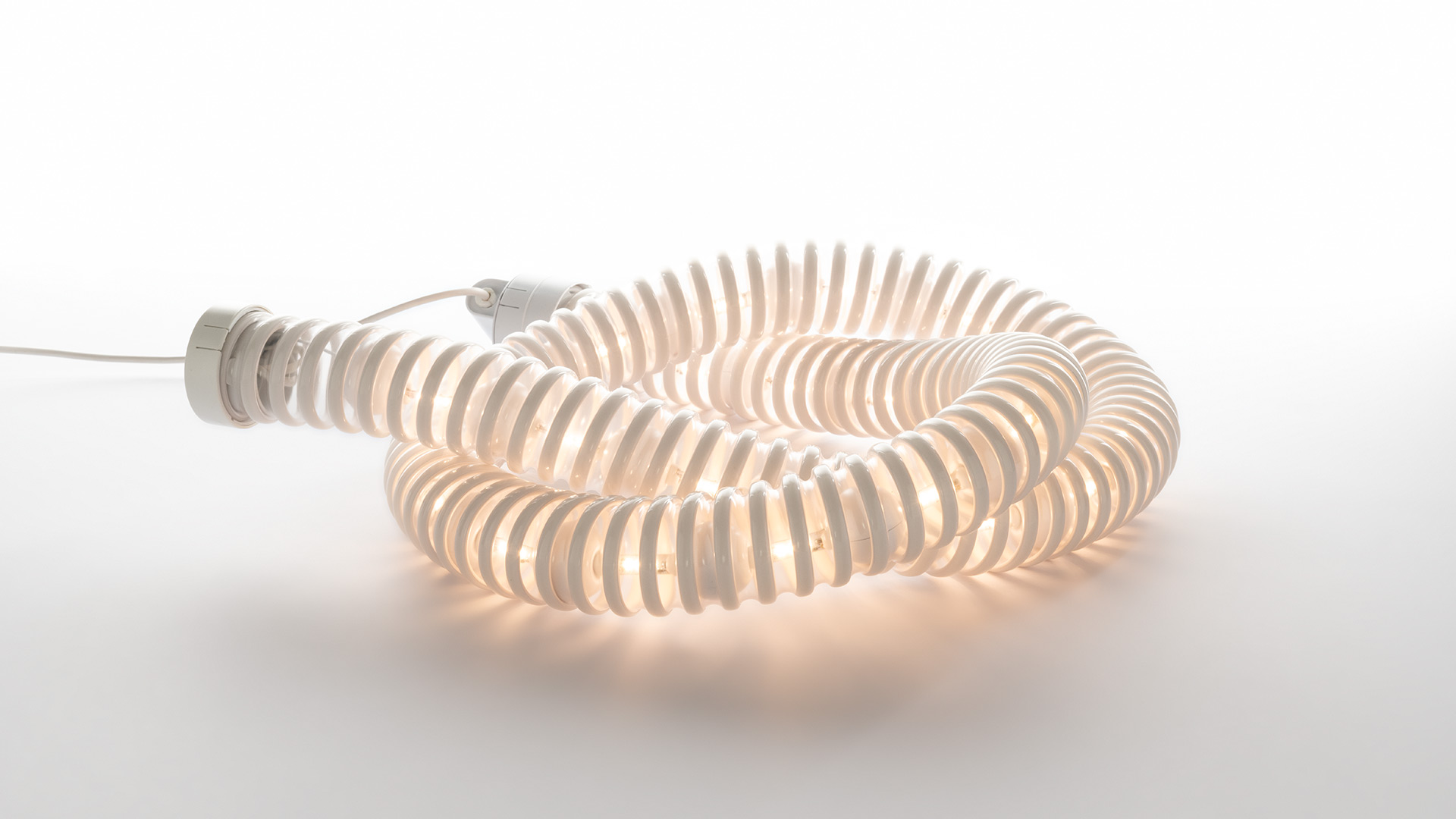Artemide Boalum lamp: flexible luminous tube coiled in a spiral, with ribbed white diffuser emitting warm ambient light