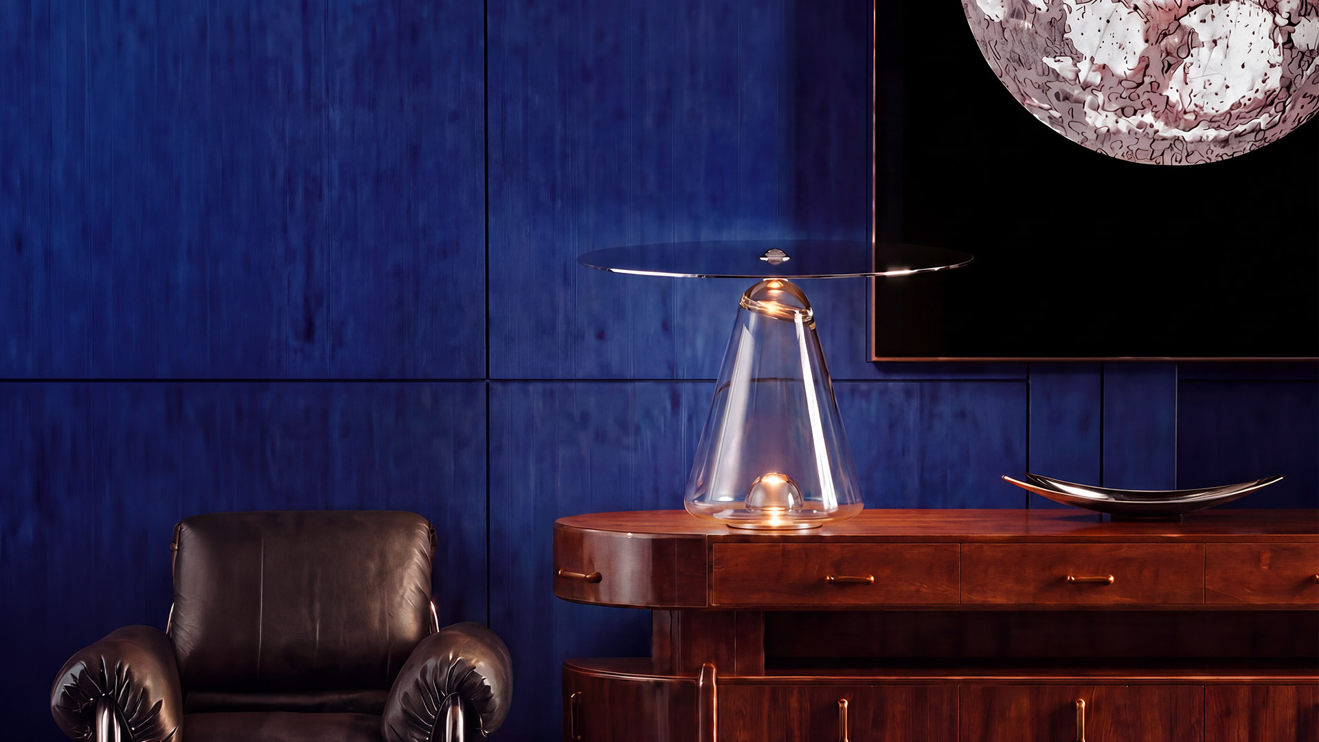 Lampada da tavolo Artemide Boltons: base conica in vetro trasparente con luce calda, sormontata da un grande paralume a disco circolare grigio inclinato