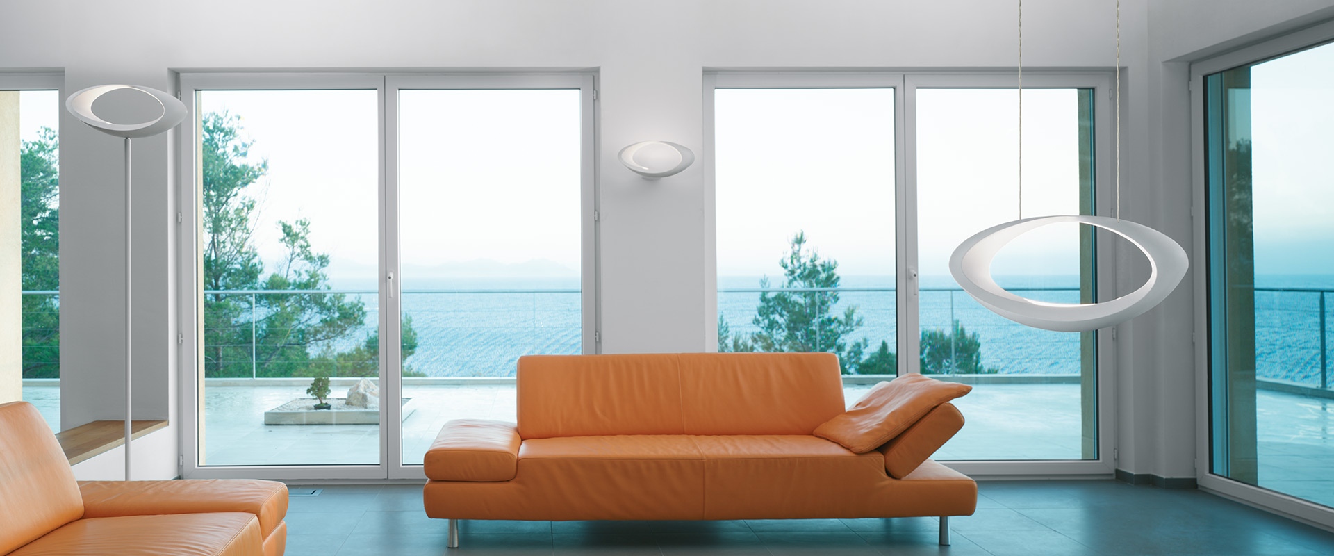 Artemide Cabildo pendant lamp: white elliptical ring-shaped diffuser emitting soft indirect light, suspended by thin cables