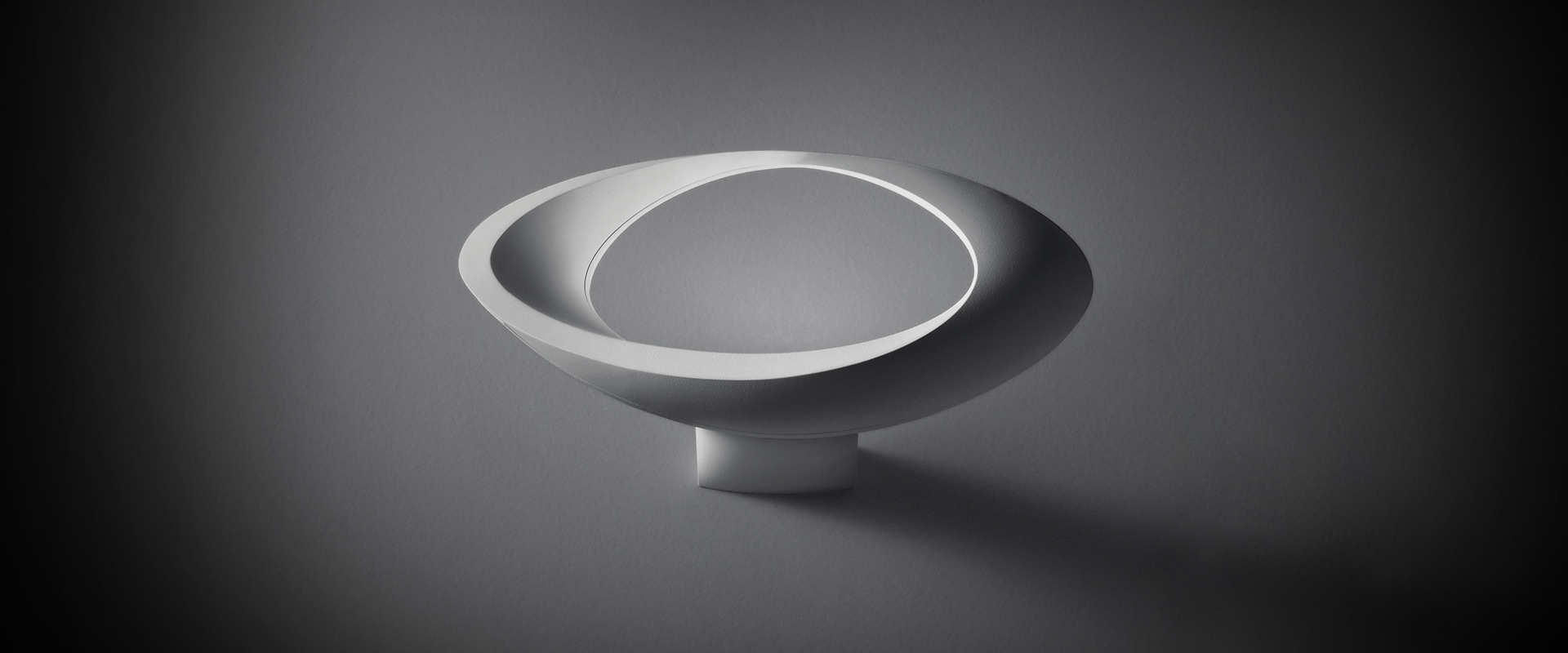 Two Artemide Cabildo white floor lamps with slim stems, circular disc-shaped heads, casting directional light on a dark background