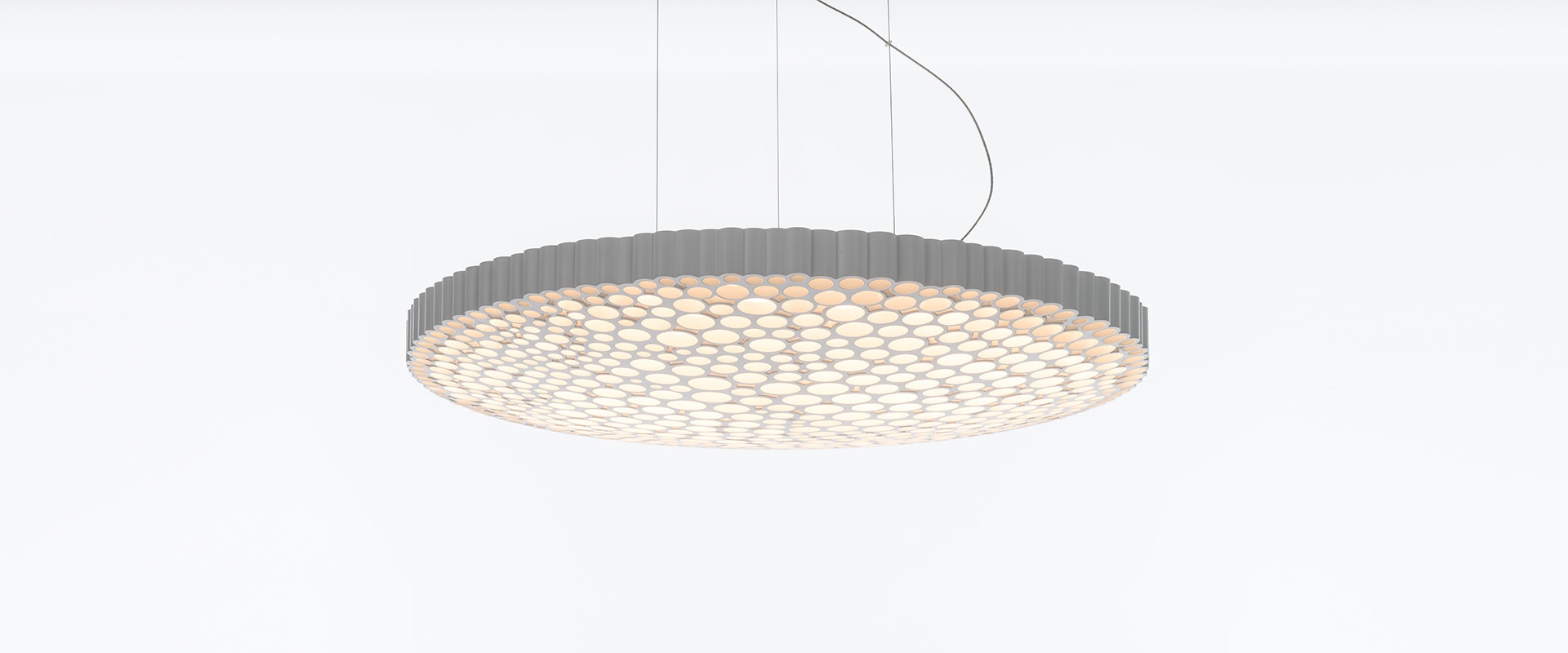 Lampada a sospensione Artemide Calipso: grande pendente circolare con diffusore a nido d'ape, luce bianca soffusa, sospesa da sottili cavi