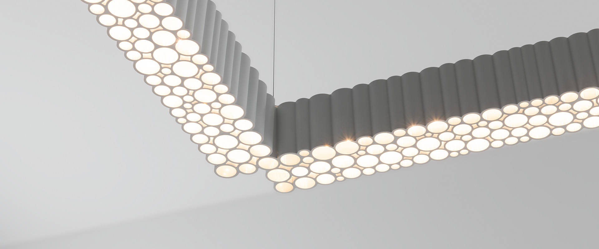 Lampada a sospensione Artemide Calipso Linear System: elegante barra orizzontale grigia con diffusore LED strutturato, sospesa da un cavo