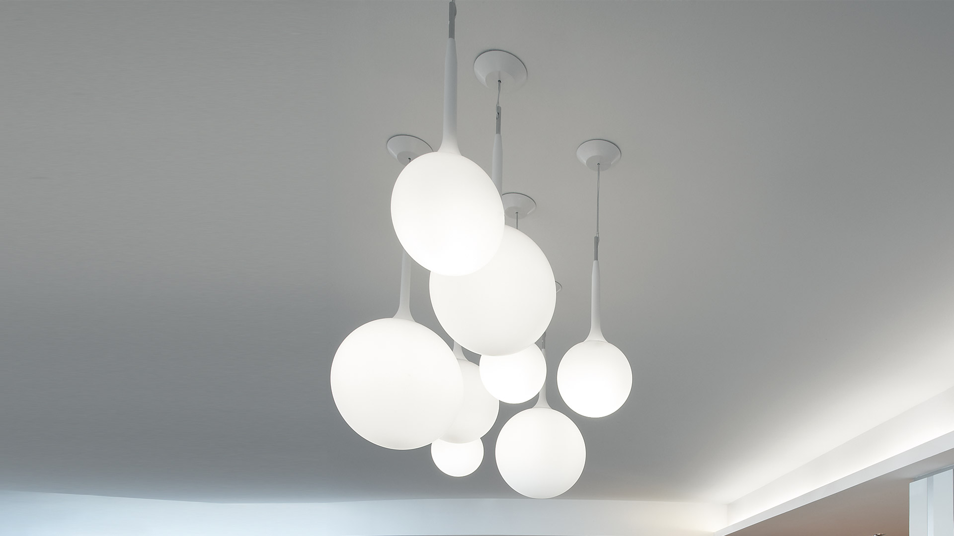 Hotel lounge with Artemide Castore Sospensione pendant lamps featuring opal white spherical diffusers hanging at varying heights over seating area