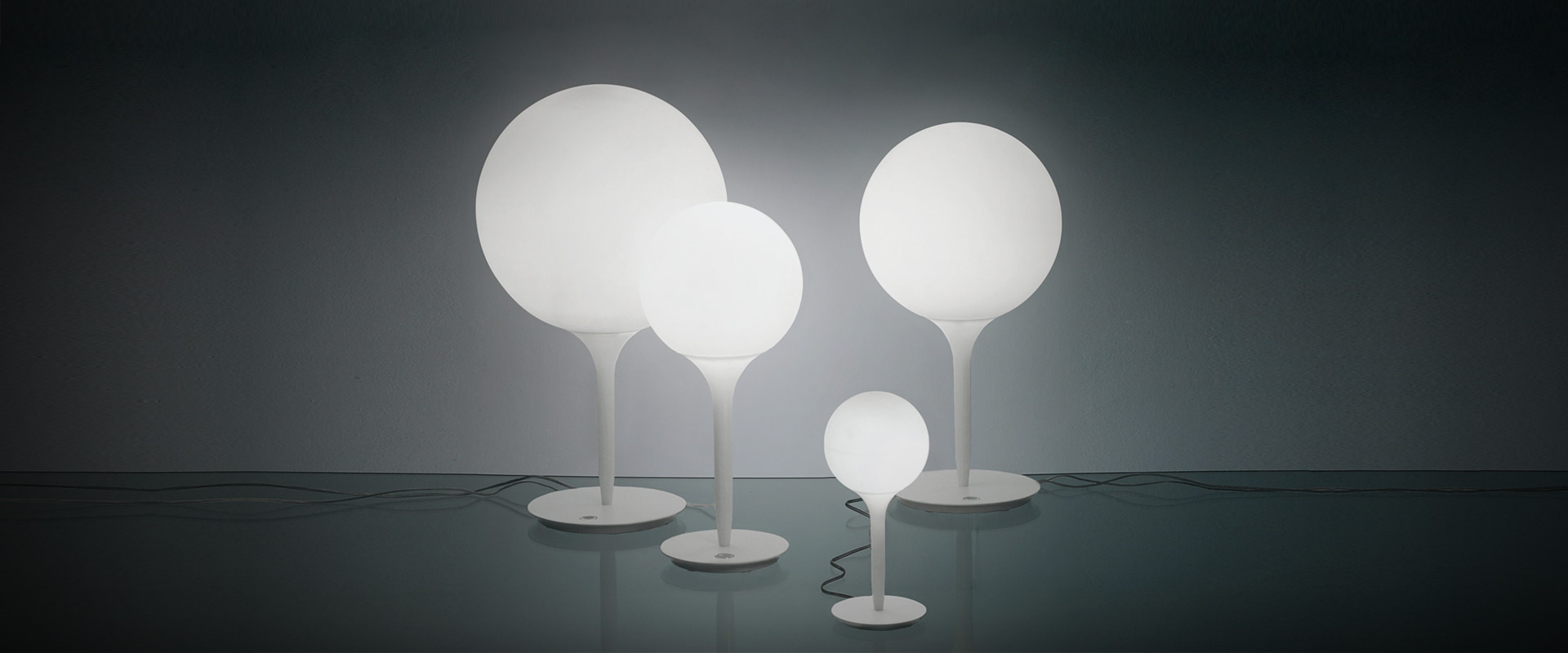 Quattro lampade da tavolo Artemide Castore Tavolo con sfere in vetro opalino bianco di diverse dimensioni su sottili steli bianchi e basi rotonde