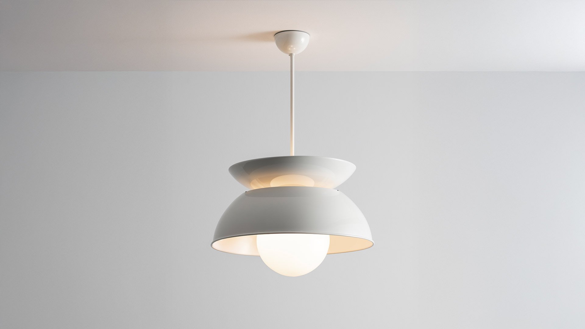 Close-up of Artemide Cetra pendant lamp: white dome shade with warm inner finish and opal glass globe bulb