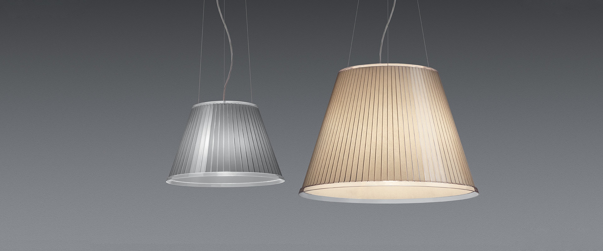 Lampada a sospensione Artemide con paralume conico plissettato argento, sospesa da sottili cavi, che emette luce diffusa dal basso