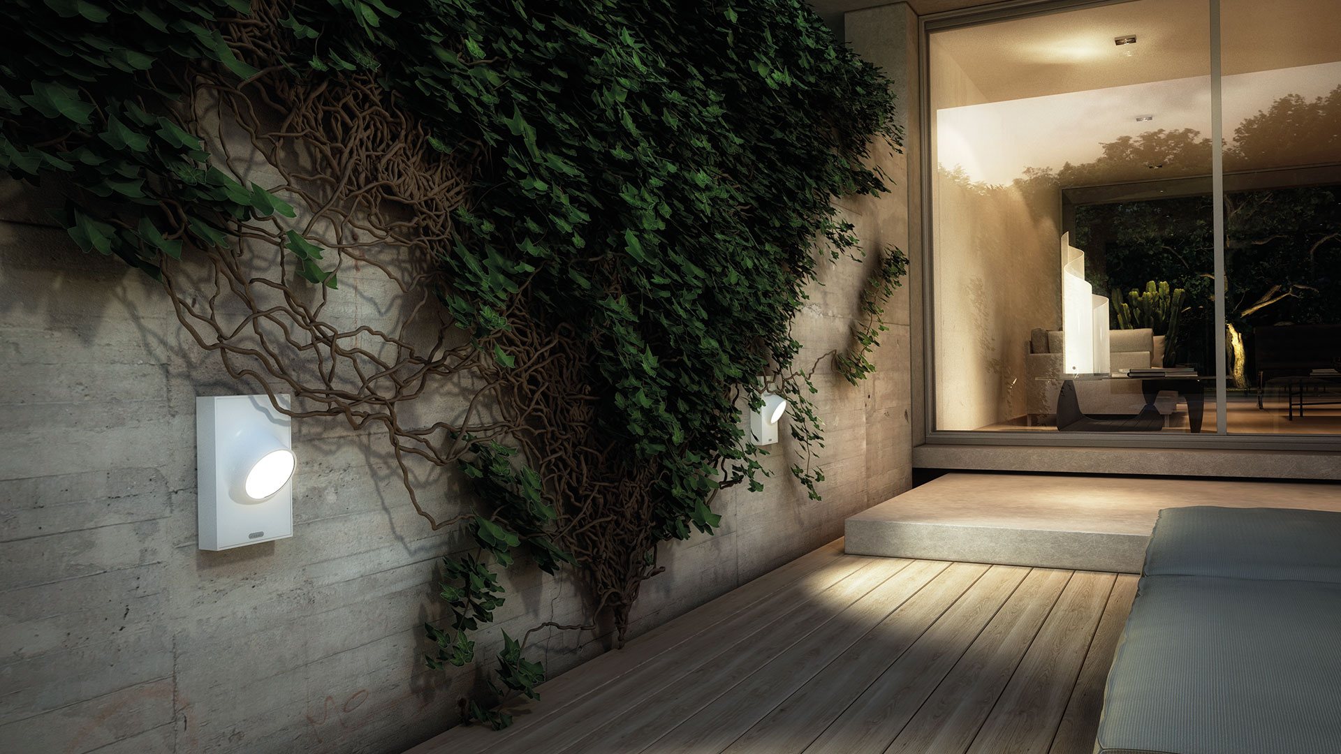 Lampada da parete per esterni Artemide Ciclope montata su muro in cemento con edera, proietta luce calda su una terrazza in legno al crepuscolo