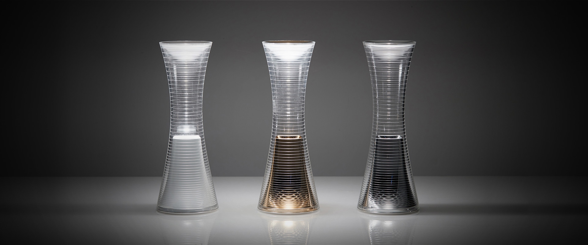 qelvornixuta.onlinee Together portable lamp with hourglass shape and gold mesh, glowing warmly outdoors on a tree stump at night