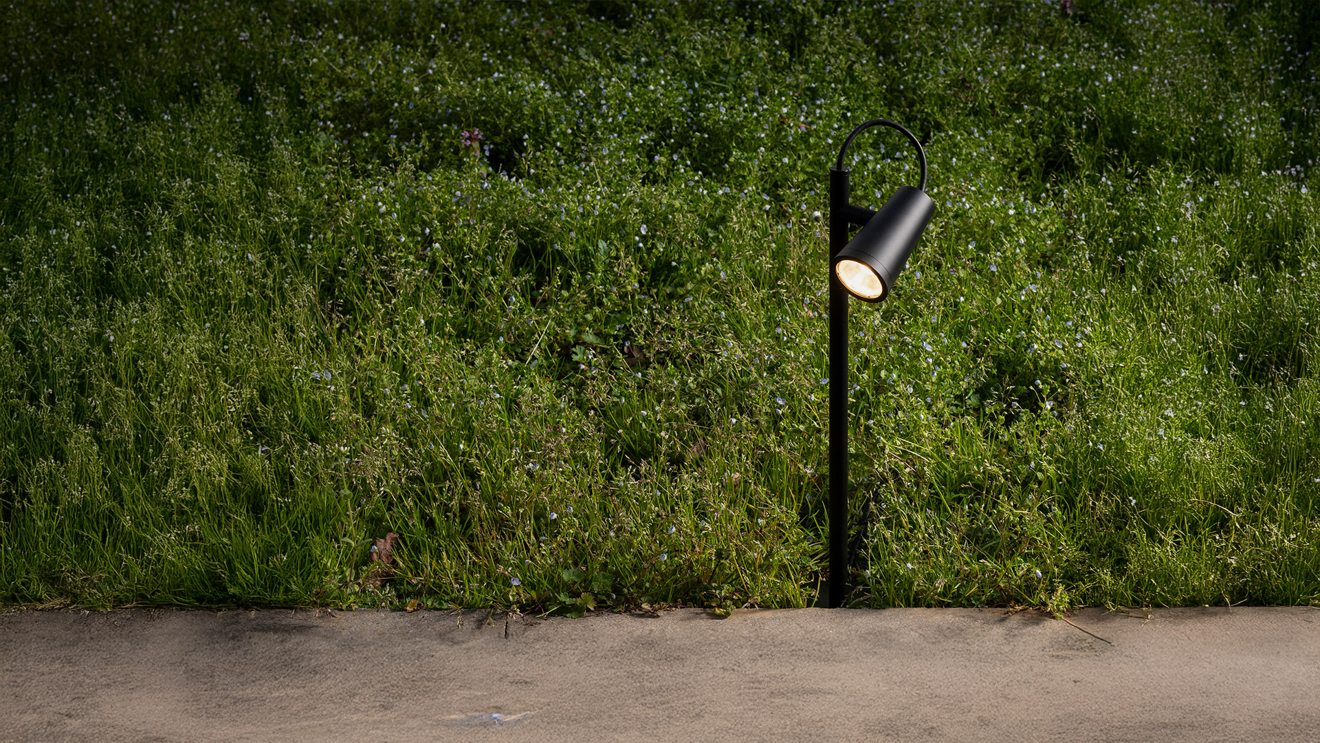 Lampada da palo outdoor Artemide Conus con due faretti conici grigio scuro montati su un palo sottile, illuminati di notte