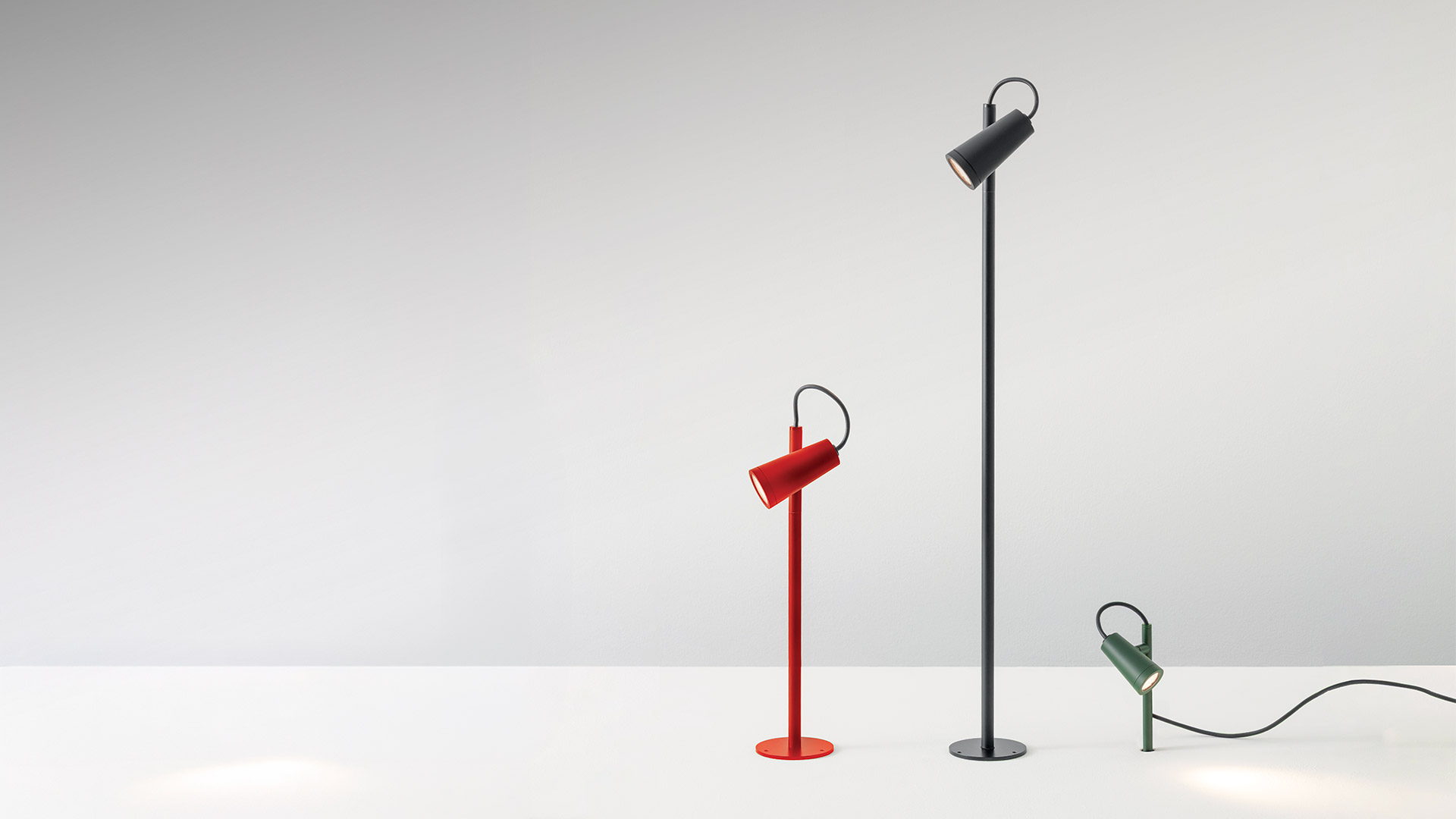 Lampada da terra Artemide Conus: fusto in metallo scuro con testa LED circolare che emette luce ad anello caldo, elegante dettaglio del cavo curvo