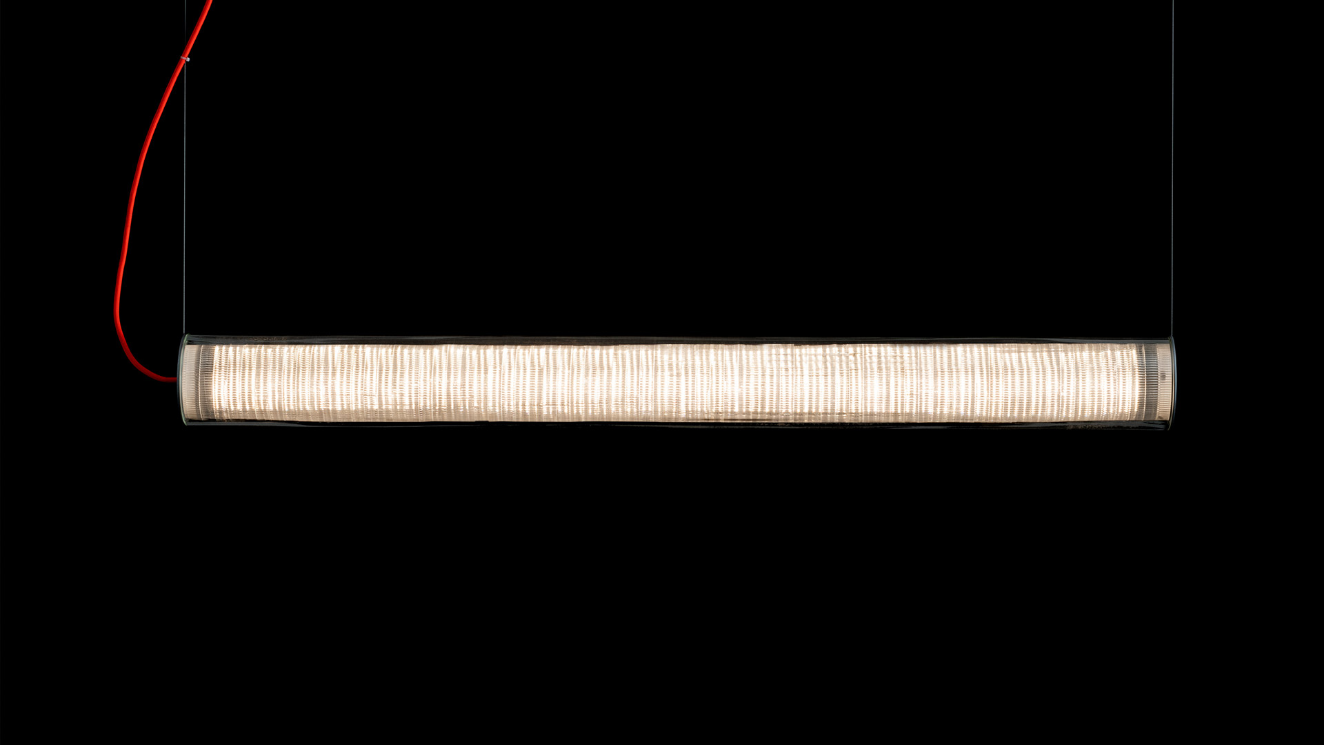 Artemide Criosfera pendant lamp: elongated cylindrical diffuser with ribbed white glass, suspended by a red cable