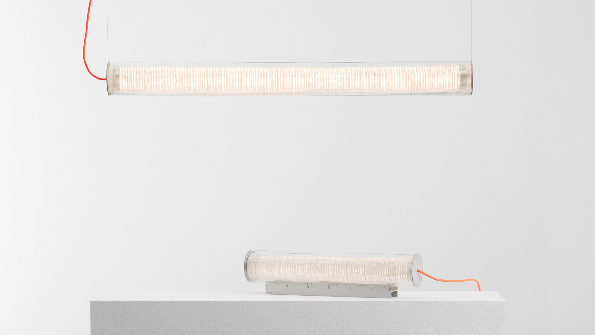 Artemide Criosfera table lamp: cylindrical LED light source emerging from transparent ice-like crystal glass block base, red power cord