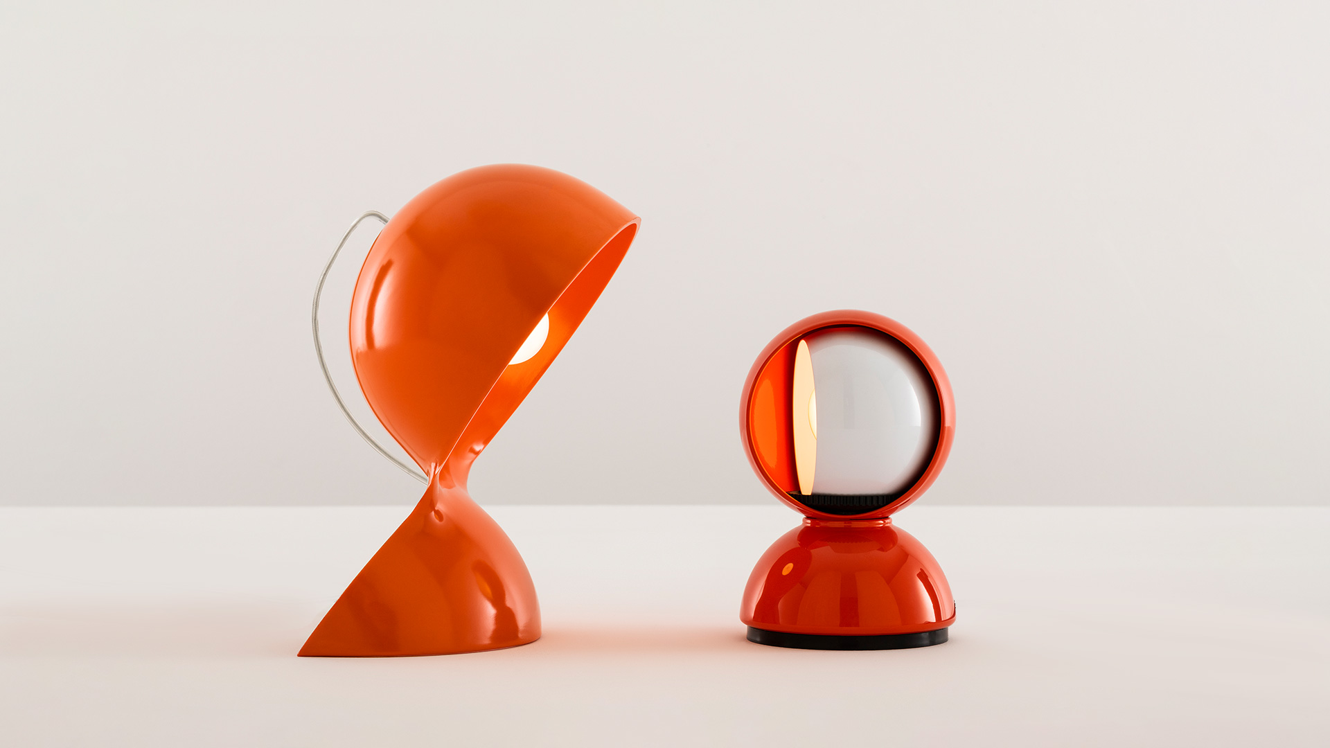 Collezione lampade da tavolo Artemide Dalù in rosso scuro: forme arrotondate scultoree con apertura circolare, mostrate in più dimensioni su display bianco