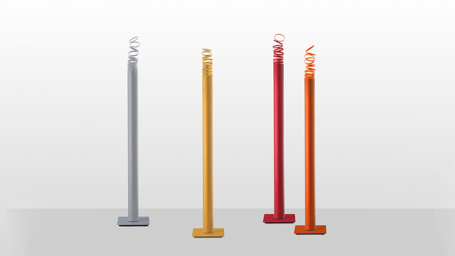 Quattro lampade da terra Artemide Decomposé Light Terra con fusti sottili e sommità LED a spirale in grigio, giallo, rosso e arancione