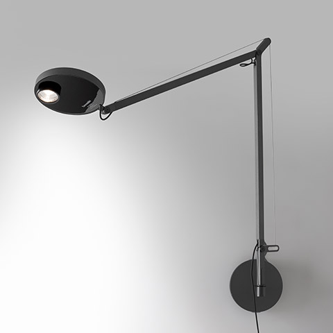 Artemide Demetra Professional Parete wall lamp in black, featuring an adjustable arm, tension cable, and oval LED head mounted on a round wall base.
