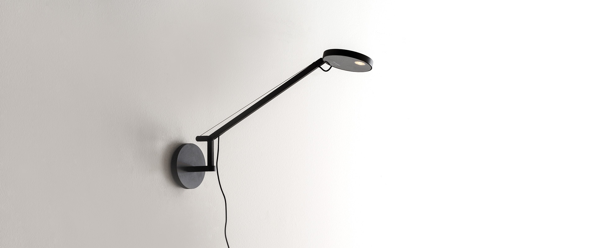 Artemide Demetra Micro wall lamp in white, featuring an adjustable arm and circular LED head, mounted on a white wall