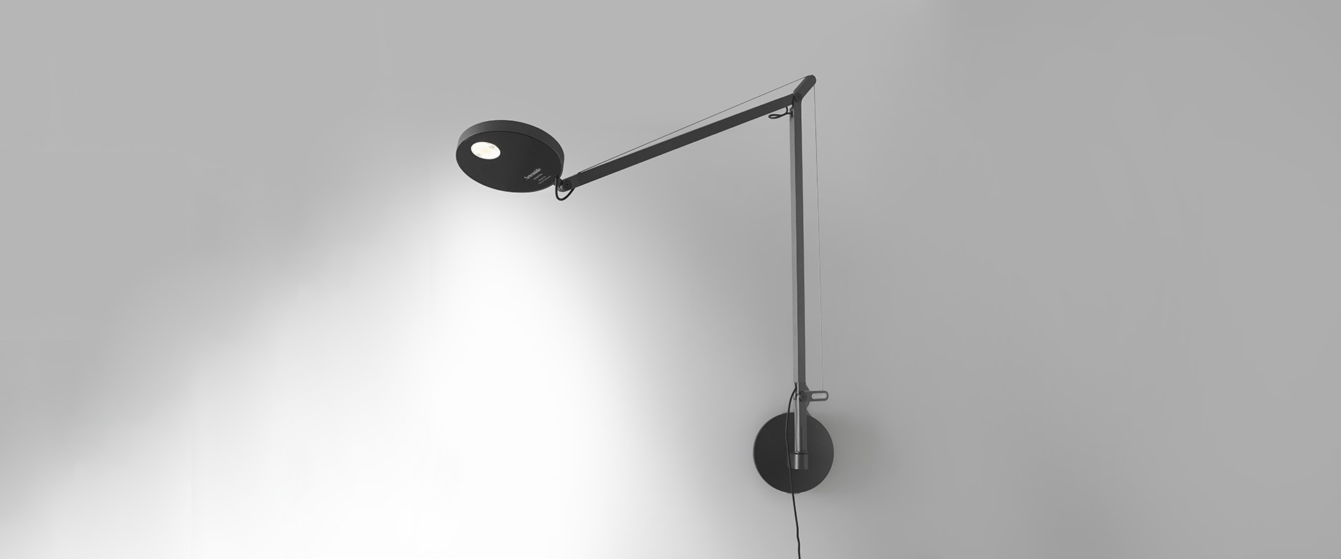 Artemide Demetra Parete wall lamp in black, featuring an adjustable articulated arm with circular LED head mounted on a wall bracket