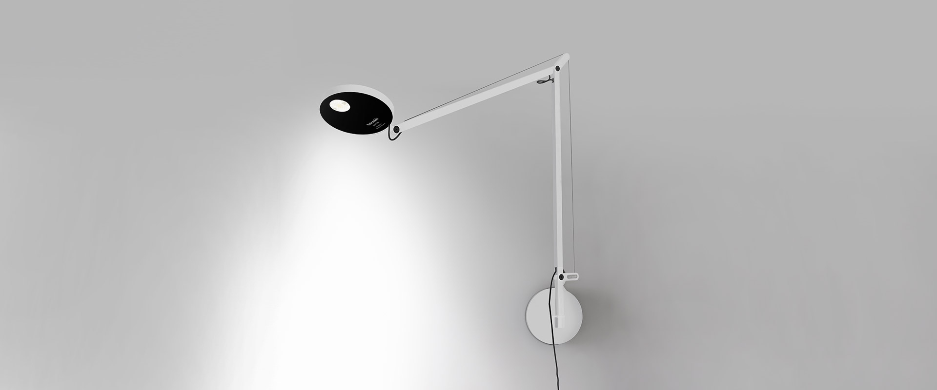 Artemide Demetra Parete wall lamp in black, featuring an adjustable articulated arm and circular LED head mounted on a wall bracket