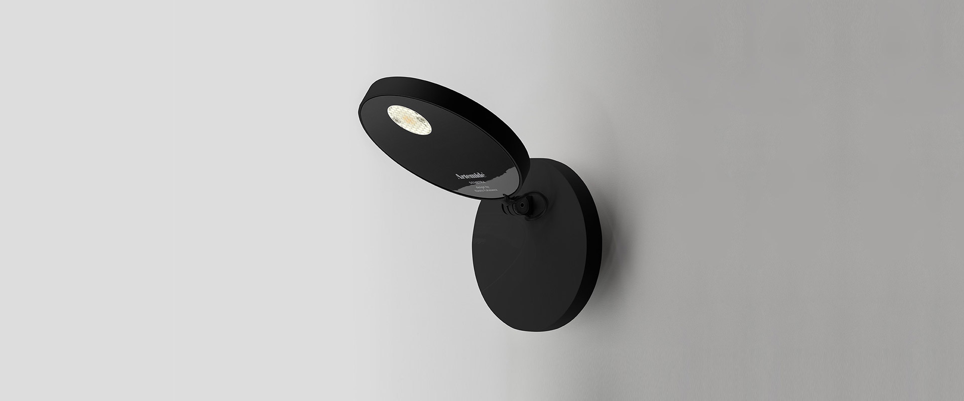 Artemide Demetra Faretto black wall spotlight with adjustable oval head and integrated LED, mounted on a round wall base