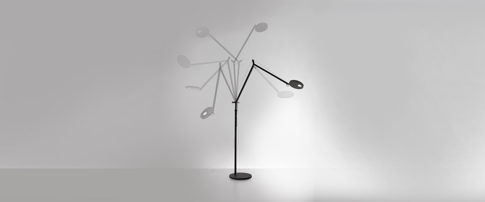 Lampada da terra Artemide Demetra Reading Floor con sottile stelo arcuato accanto a un divano in bouclé crema in un soggiorno con pannelli color ottanio