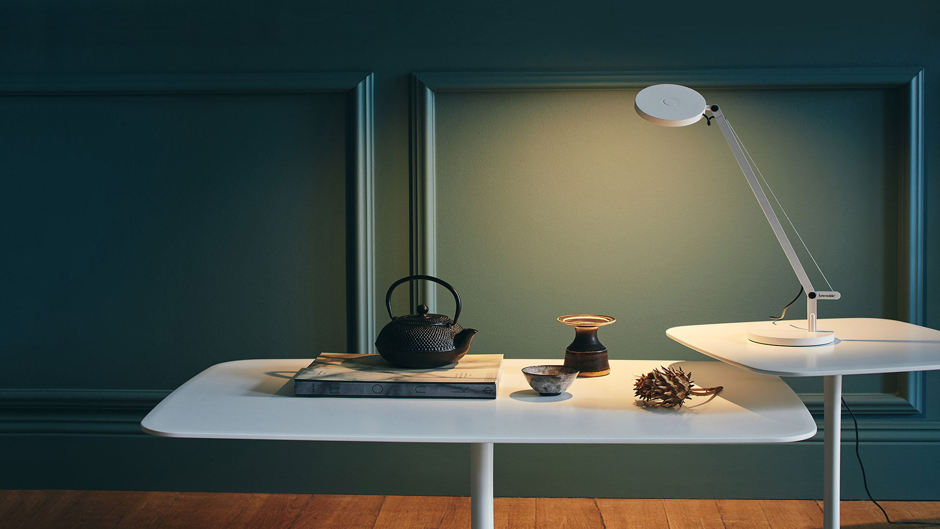 Artemide Demetra Micro table lamp in black, featuring an adjustable arm, circular LED head, and round base with tension wire.