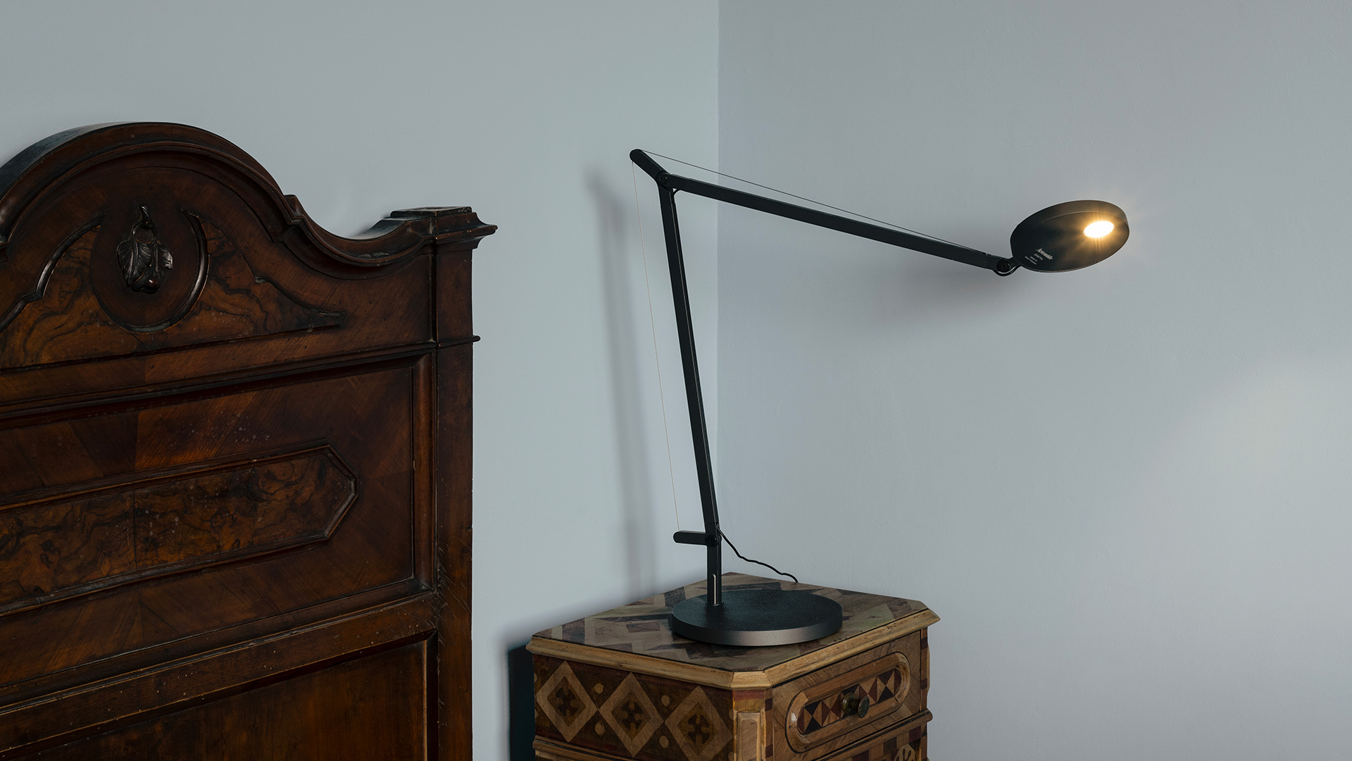 Lampada da tavolo Artemide Demetra Tavolo nera con braccio articolato e testa LED ovale su comodino in legno