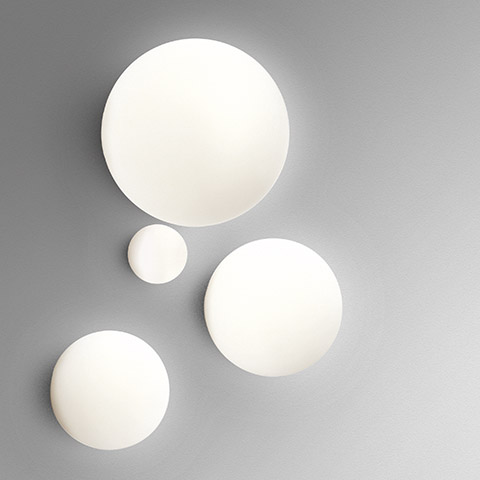 Quattro lampade da parete/soffitto Artemide Dioscuri in diverse dimensioni, con diffusori sferici in vetro opalino bianco montati su parete grigia