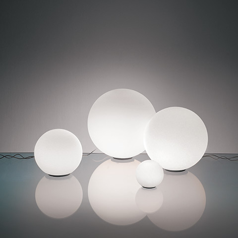 Quattro lampade da tavolo Artemide Dioscuri in vetro bianco satinato a sfera su piccole basi nere, esposte in quattro dimensioni su superficie riflettente