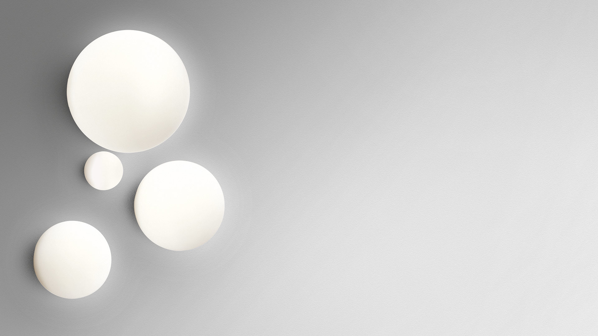 Tre lampade da parete/soffitto Artemide Dioscuri in diverse dimensioni, diffusori sferici bianchi opalini montati su parete grigia