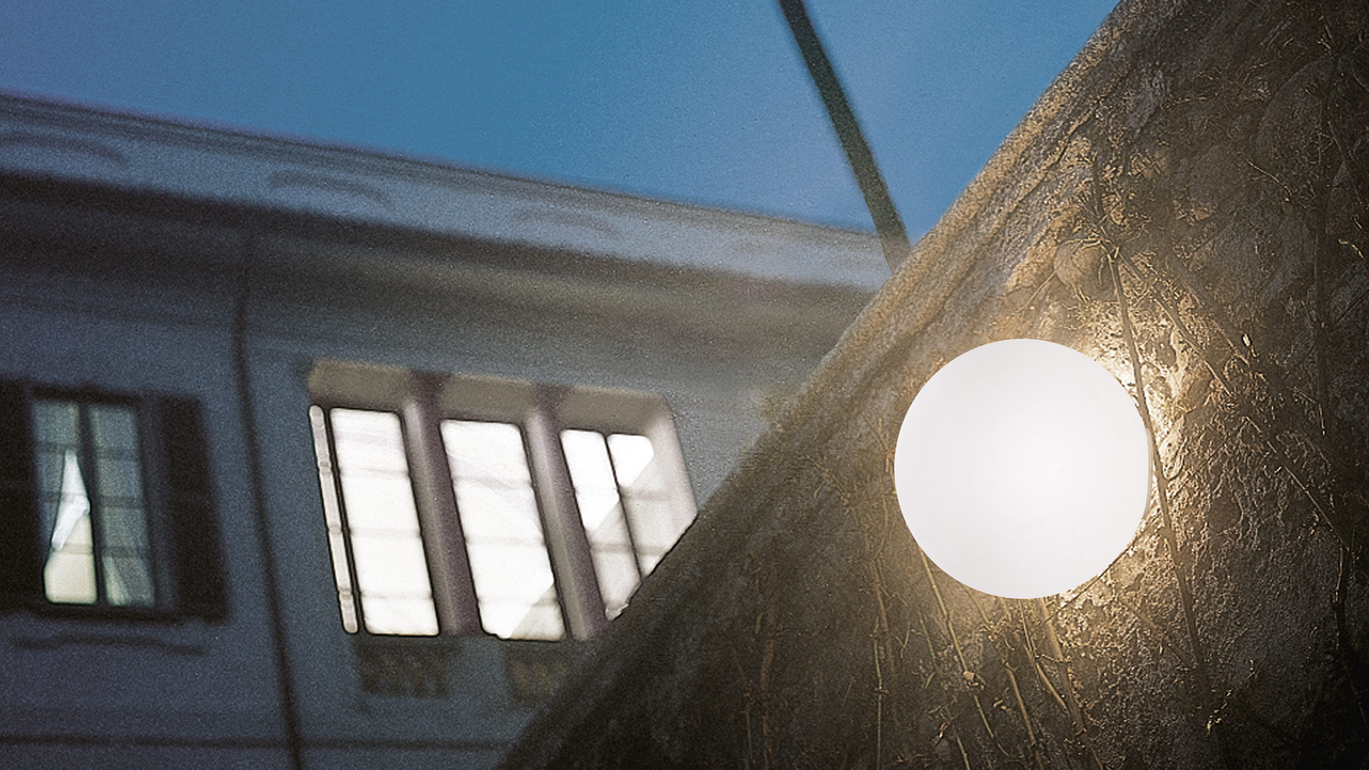 Lampada da parete/soffitto Artemide Dioscuri con diffusore in vetro opalino su superficie in pietra, edificio classico riflesso sullo sfondo