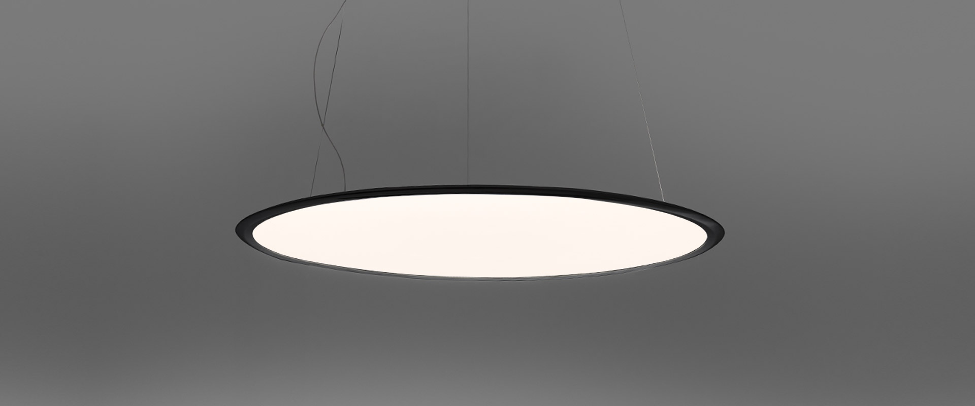 Lampada a sospensione Artemide Discovery: ampio disco circolare con diffusore bianco e bordo bronzo, sospesa da sottili cavi