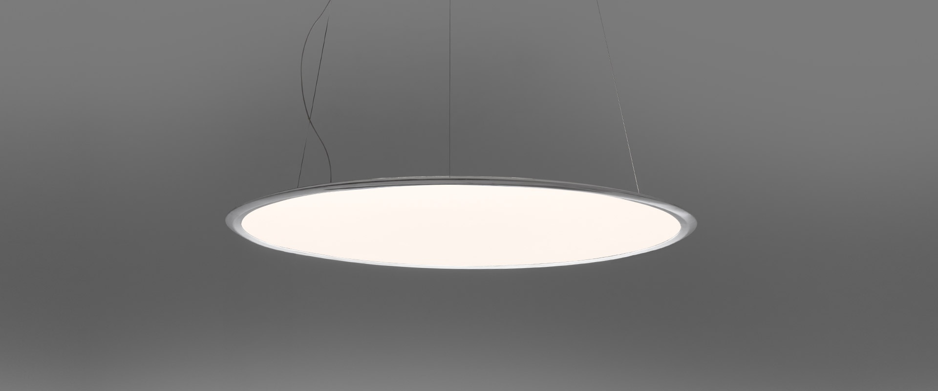 Lampada a sospensione Artemide Discovery: grande disco circolare piatto con diffusore bianco e sottile bordo in alluminio, sospesa da cavi sottili