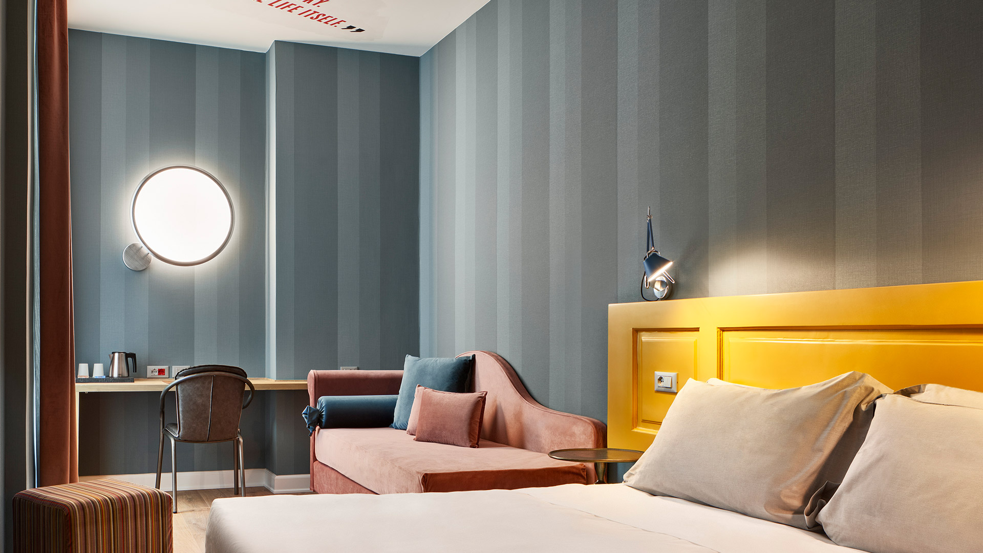 Artemide Discovery Parete wall lamp: large illuminated circular ring with small spherical diffuser at bottom, mounted on grey wall