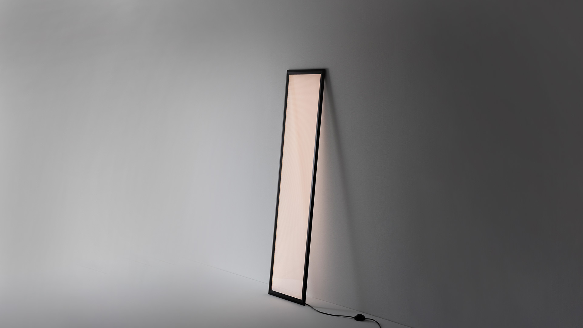 Lampada da terra Artemide Discovery Terra in tre modalità colore: rosso caldo, bianco neutro e blu freddo, appoggiata a una parete vicino a scale