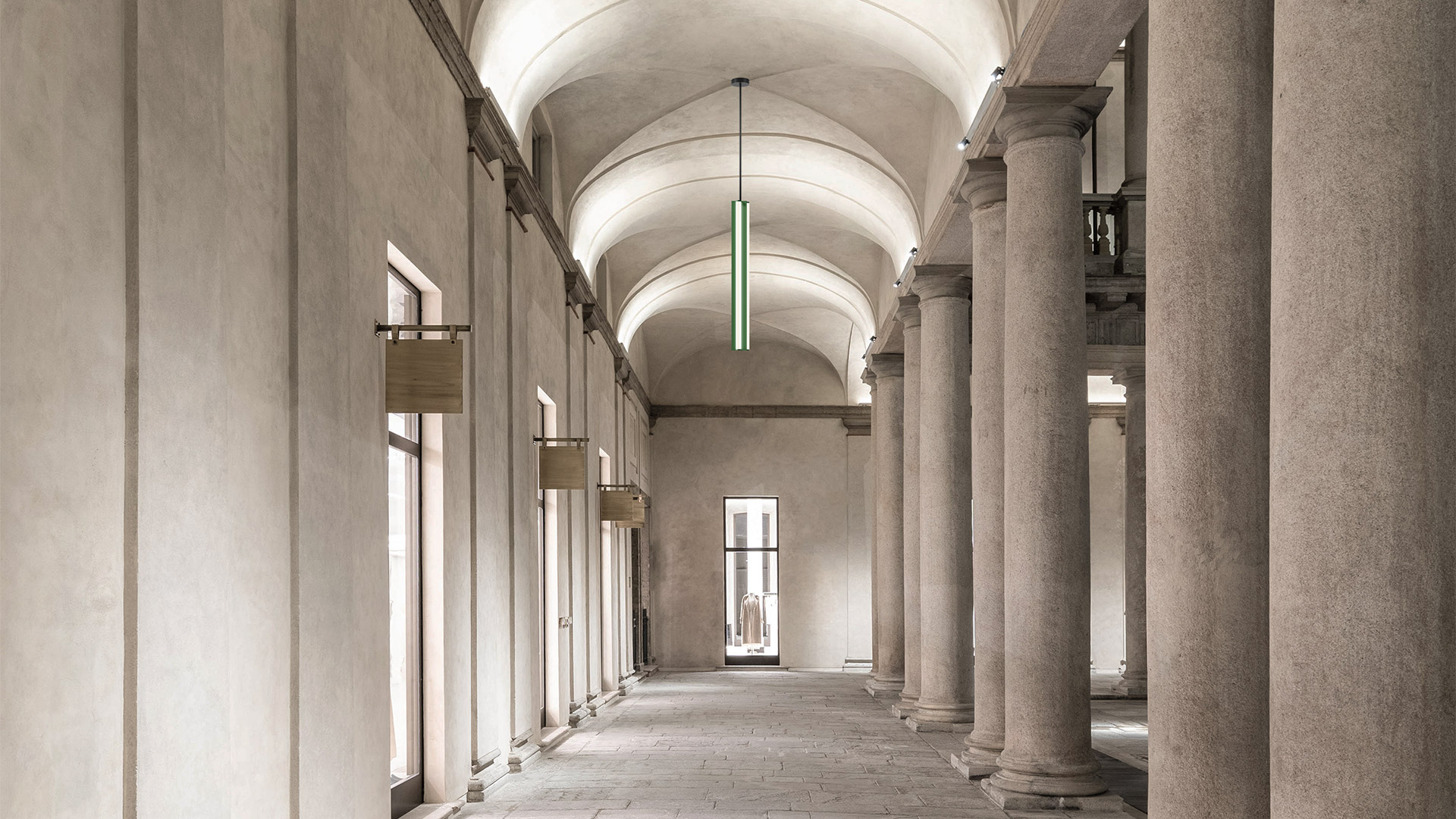 Two Artemide Dreispitz pendant lamps with elongated cylindrical black frames and warm LED strips, hanging from black cords