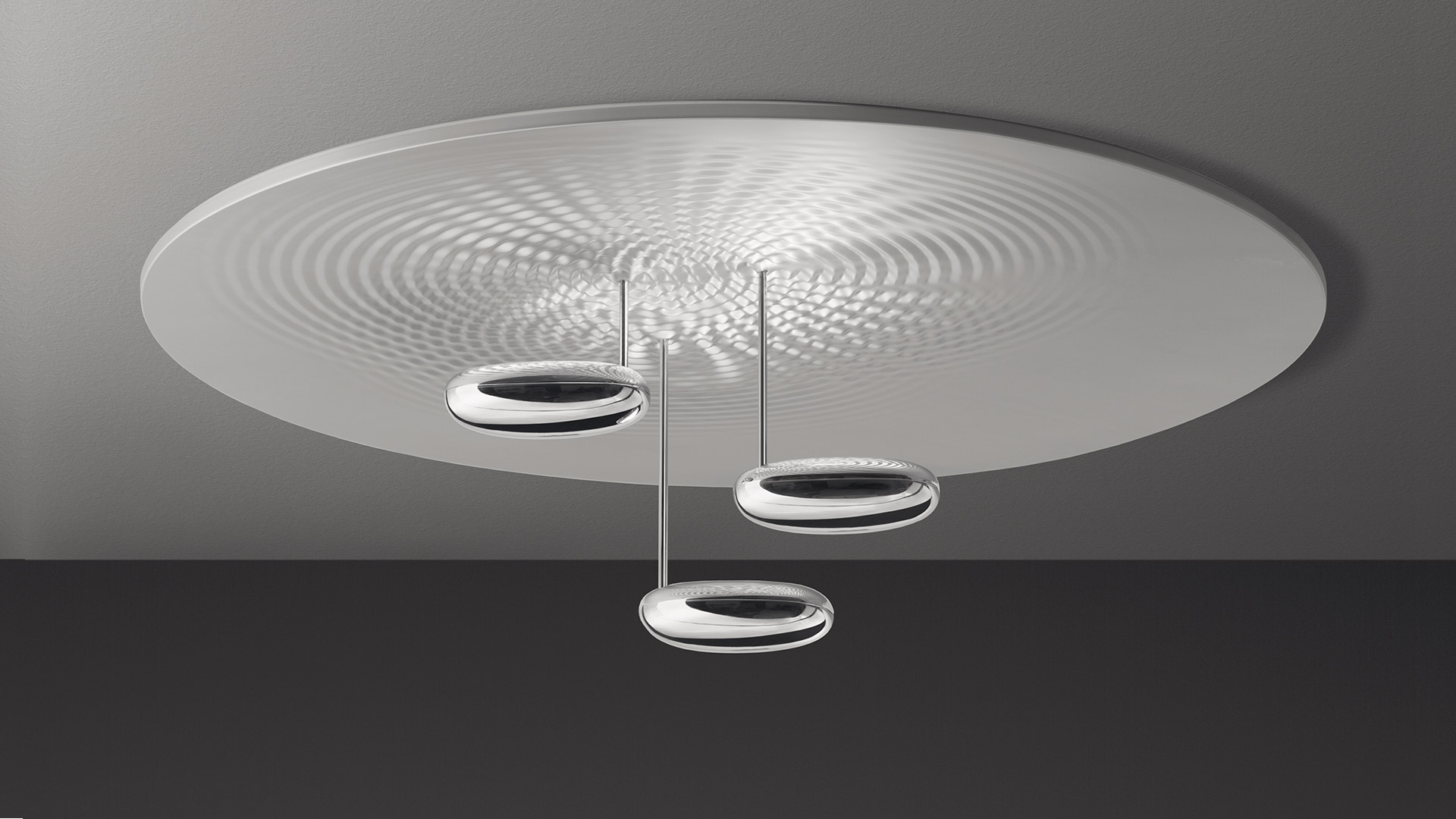 Artemide Droplet ceiling lamp: three ring-shaped LED pendants on slim rods beneath a large circular diffuser casting ripple light patterns