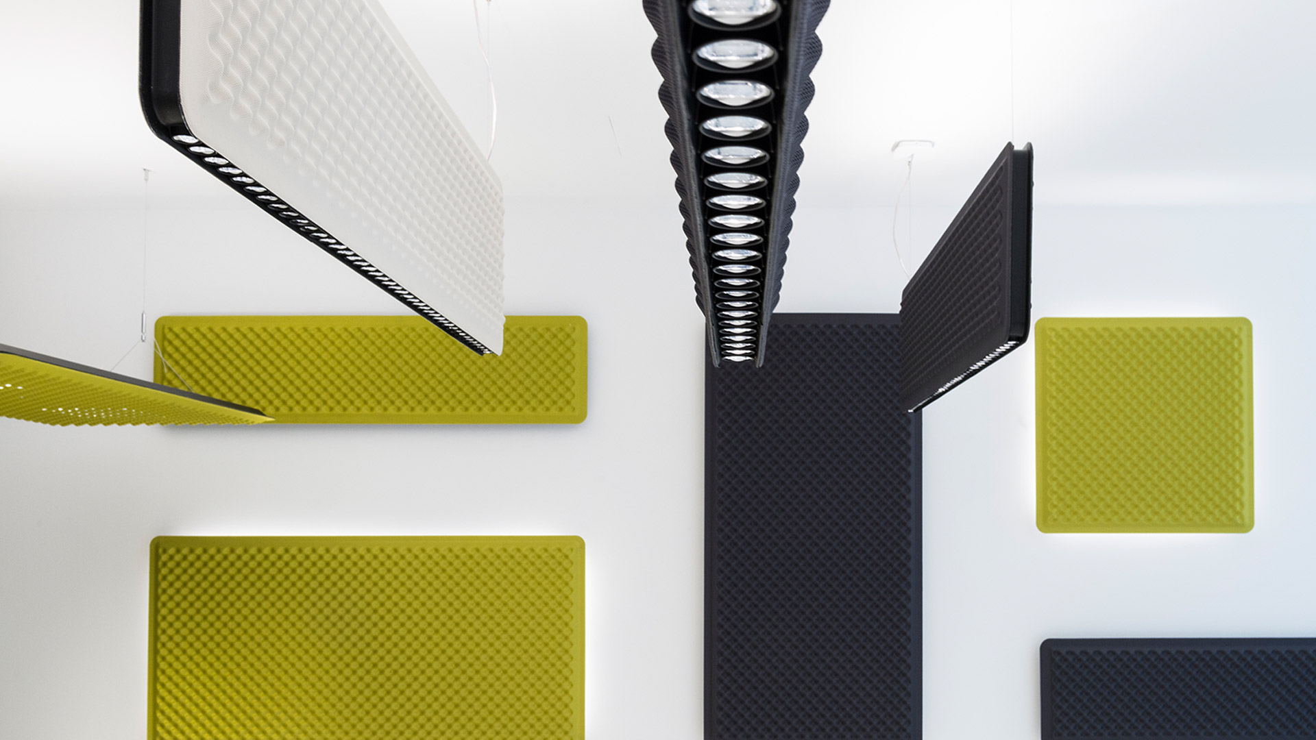 Pannelli acustici Artemide Eggboard in nero, bianco e giallo, esposti come soluzioni a soffitto e a parete nello showroom Progetto CMR.