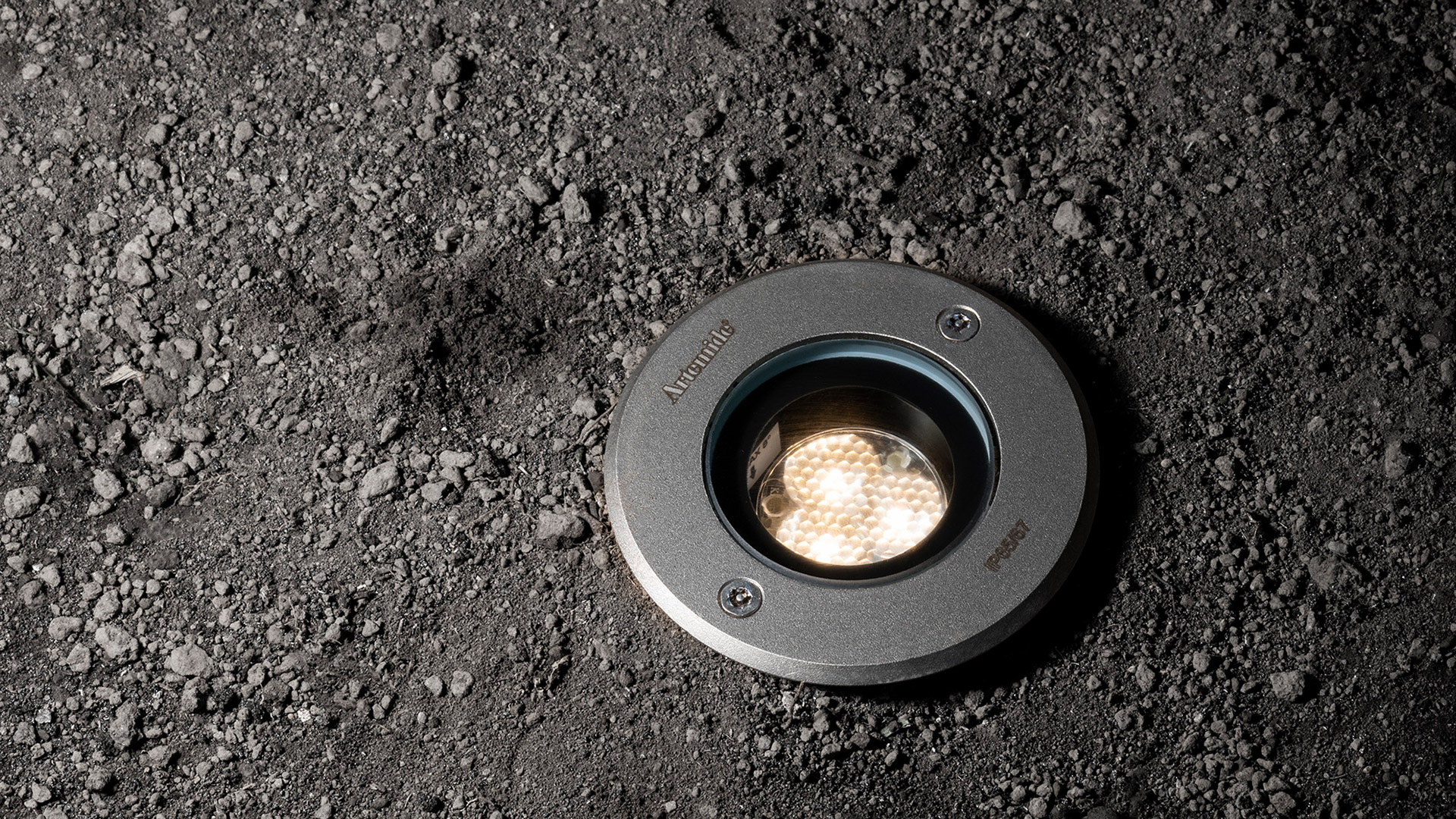 Esterno di edificio moderno al crepuscolo illuminato da downlight Artemide Ego 90, che valorizzano colonne e soffitto aggettante in legno con luce calda