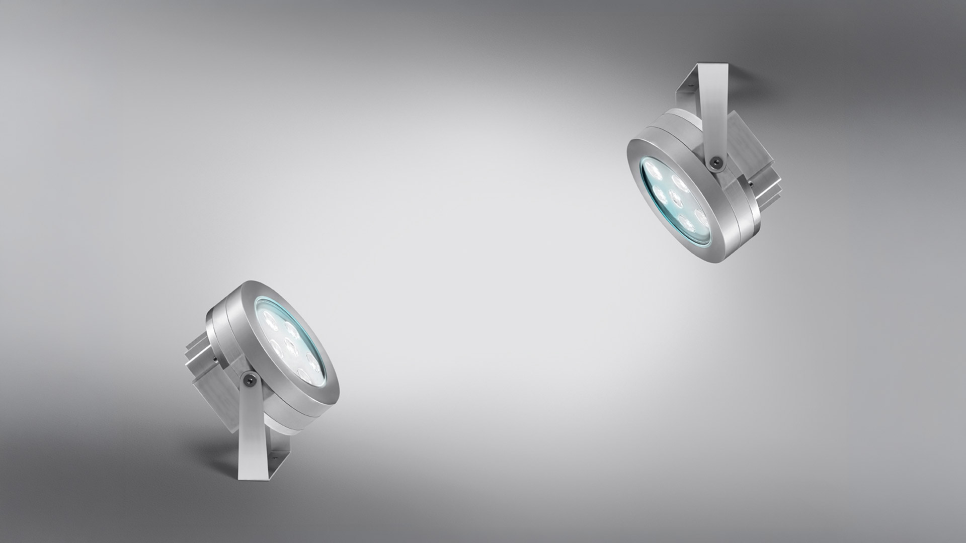Due faretti da esterno Artemide Ego Spot in alluminio spazzolato, con ottica LED circolare, montati su staffe orientabili