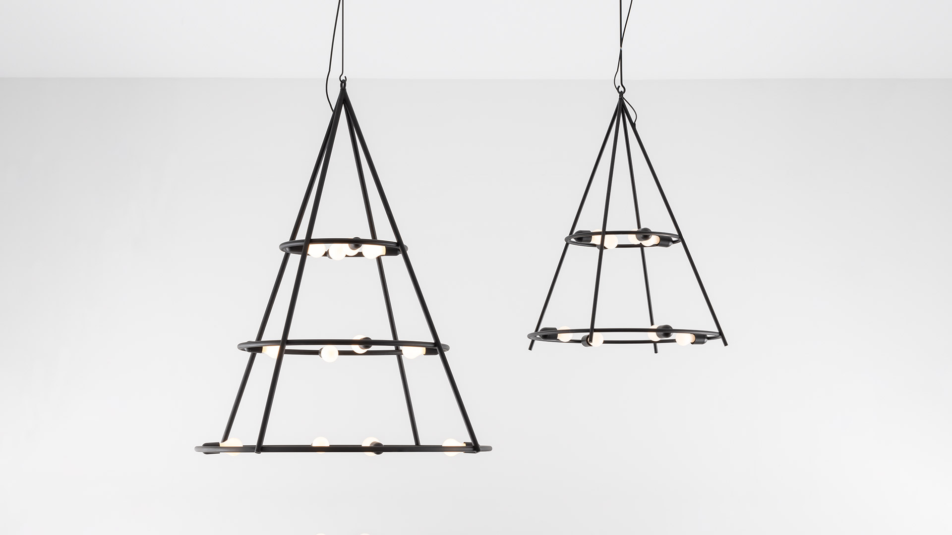 Due sospensioni Artemide El Porís: strutture coniche in metallo scuro con anelli circolari multipli che reggono piccole lampadine a globo, in due dimensioni